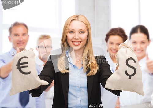 Image of businesswoman holding money bags with dollars