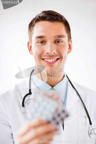 Image of young male doctor with packs of pills