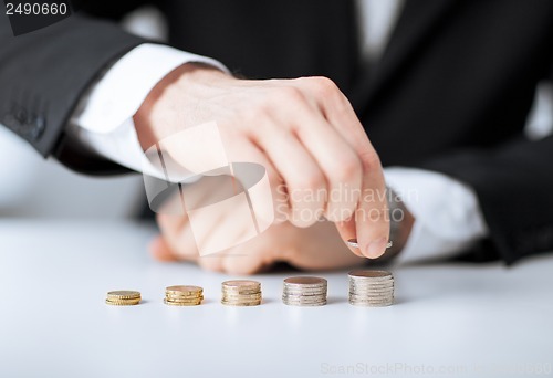 Image of man putting stack of coins into one row