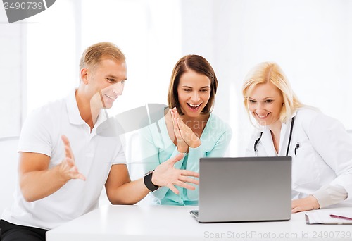 Image of doctor with patients looking at laptop