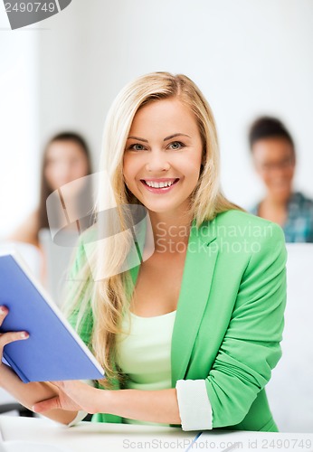 Image of smiling young girl reading book at school