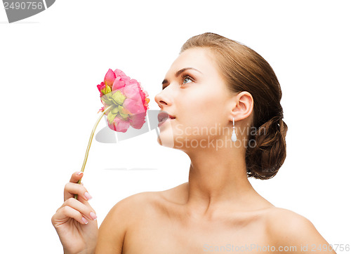 Image of woman wearing earrings and smelling flower