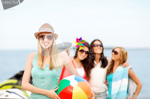 Image of girl with ball and friends on the beach