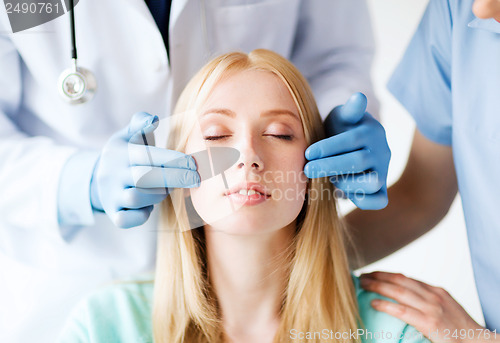 Image of plastic surgeon and nurse with patient