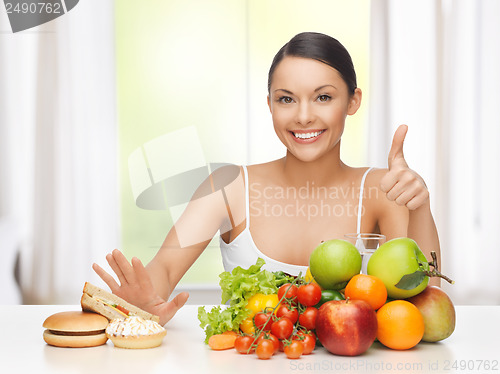 Image of woman with fruits rejecting junk food
