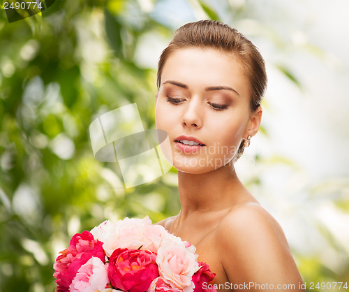 Image of woman wearing earrings and holding flowers