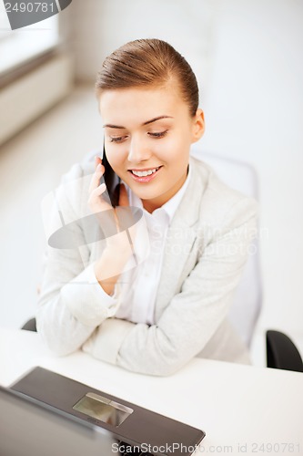 Image of businesswoman with smartphone in office