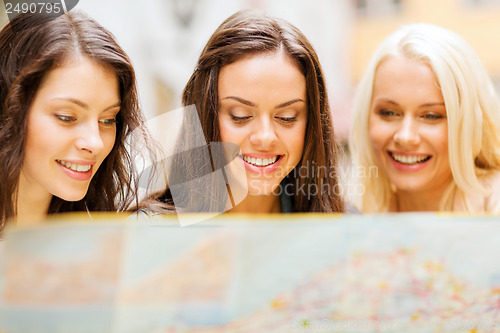 Image of beautiful girls looking into tourist map in city