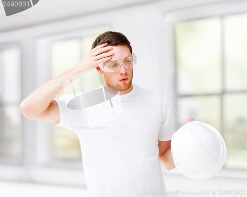 Image of male architect in safety glasses taking off helmet