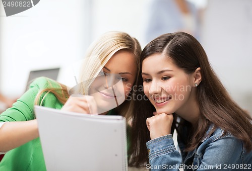 Image of student girls pointing at notebook at school