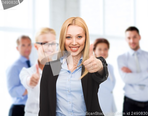 Image of businesswoman showing thumbs up in office