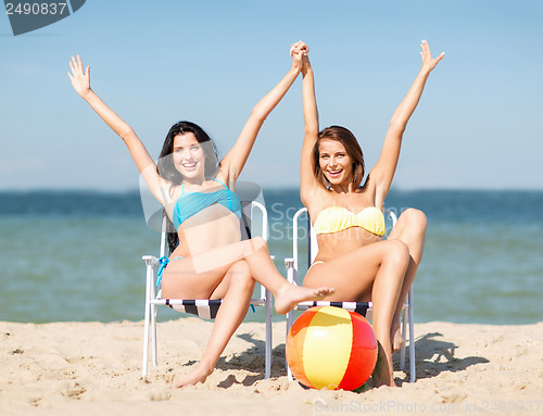 Image of girls sunbathing on the beach chairs