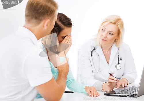 Image of doctor with patients looking at laptop