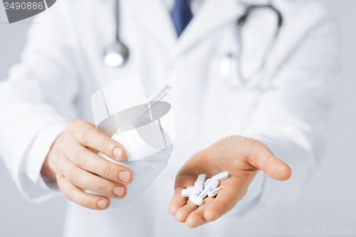 Image of doctor hands holding white pack and pills