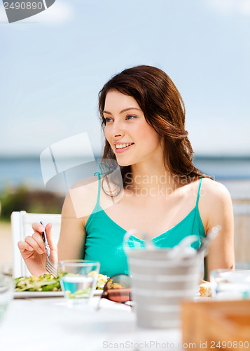 Image of girl eating in cafe on the beach