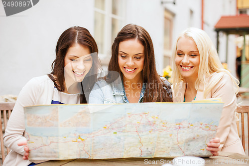 Image of beautiful girls looking into tourist map in city