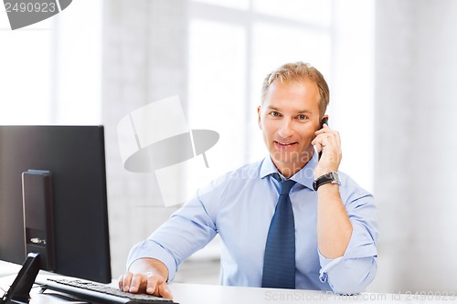 Image of smiling businessman with smartphone in office