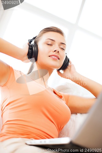 Image of woman with headphones and laptop at home