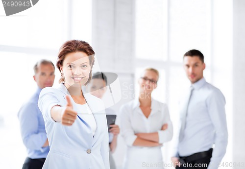 Image of businesswoman in office showing thumbs up