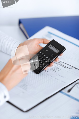 Image of woman hand with calculator and papers