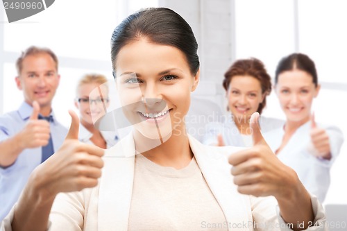 Image of businesswoman showing thumbs up in office
