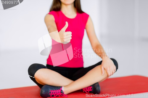 Image of girl sitting in lotus position with thumbs up