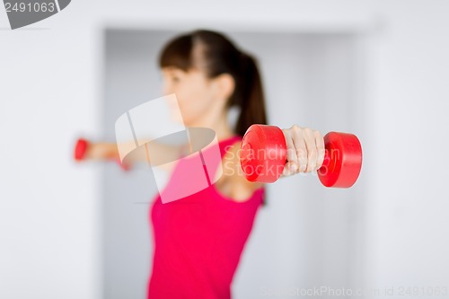 Image of sporty woman hands with light red dumbbells