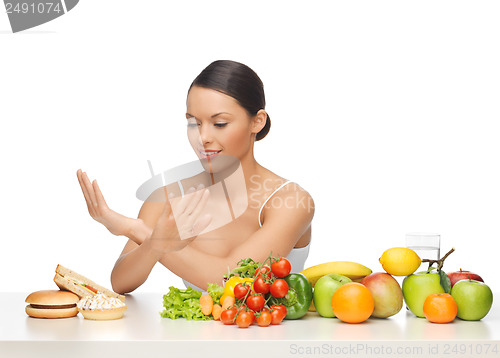 Image of woman with fruits rejecting hamburger