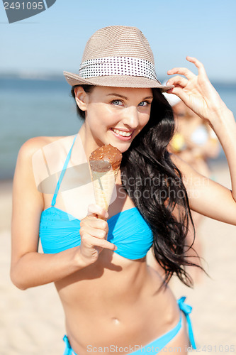 Image of girl in bikini eating ice cream on the beach