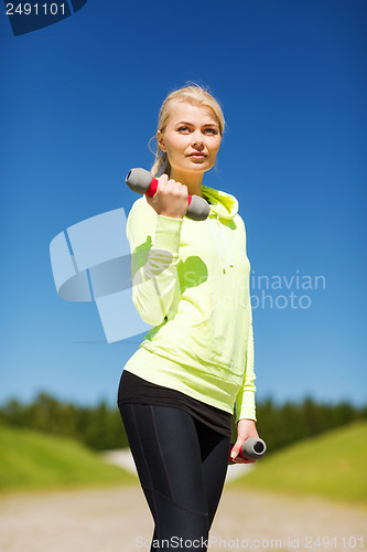Image of sporty woman with light dumbbells outdoors