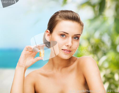 Image of beautiful woman showing bottle with golden dust