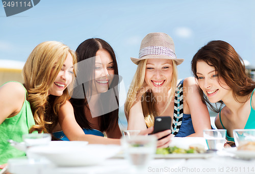 Image of girls looking at smartphone in cafe on the beach