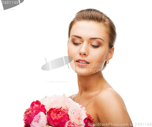 Image of woman wearing earrings and holding flowers