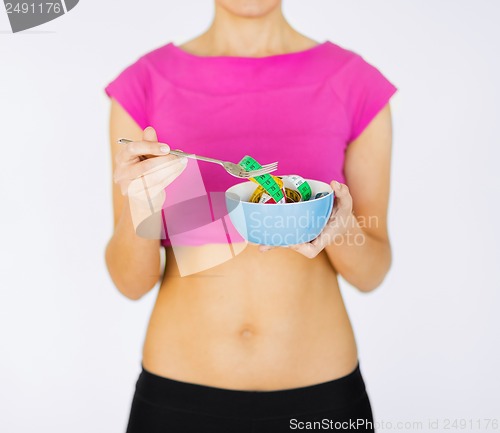 Image of woman hands holding bowl with measuring tape