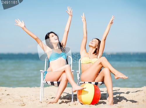 Image of girls sunbathing on the beach chairs