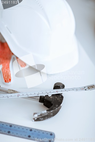Image of blueprint, flexible ruller, helmet and hammer