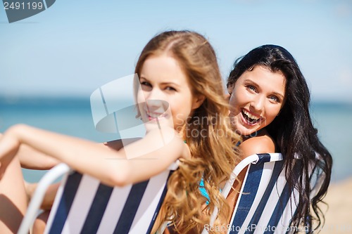 Image of girls sunbathing on the beach chairs