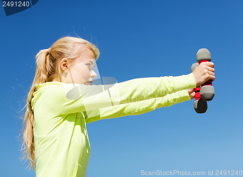Image of sporty woman with light dumbbells outdoors
