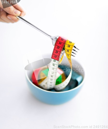 Image of woman hand with fork, bowl and measuring tape