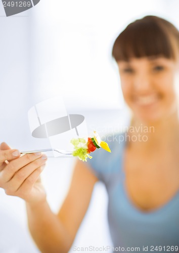 Image of woman hand holding fork with vegetables