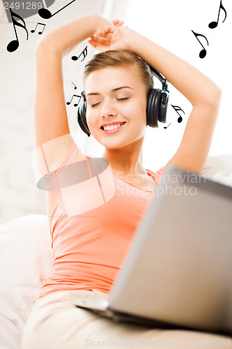Image of woman with headphones and laptop at home