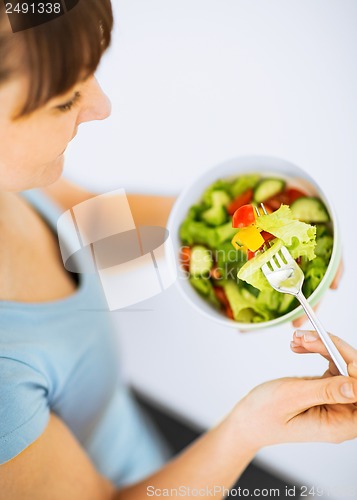 Image of woman eating salad with vegetables