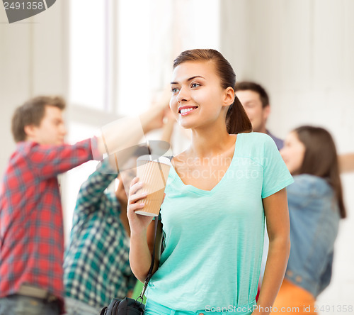 Image of student holding take away coffee cup in college