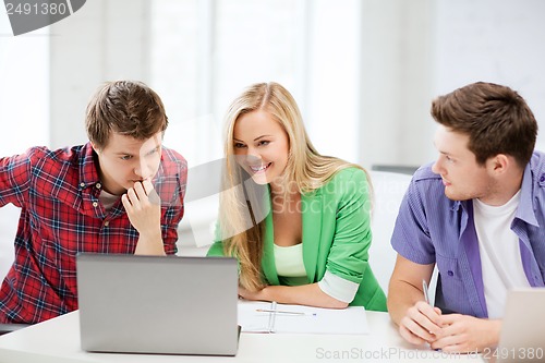 Image of smiling students looking at laptop at school
