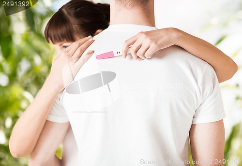 Image of woman with pregnancy test hugging man