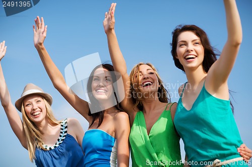 Image of girls walking on the beach and waivng hands