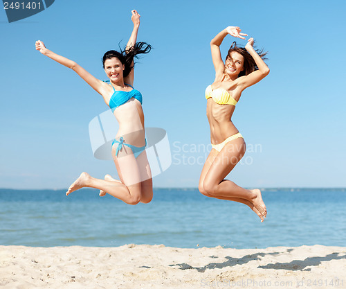 Image of girls in bikini jumping on the beach