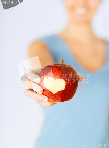 Image of woman hand holding red apple with heart shape