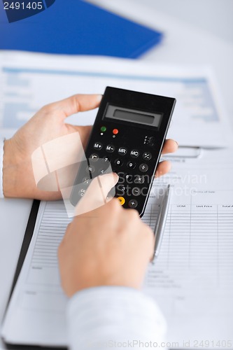 Image of woman hand with calculator and papers