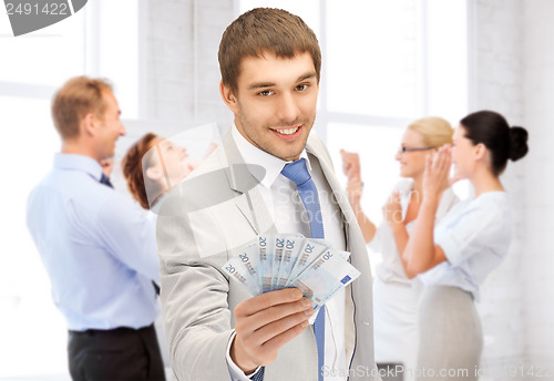 Image of happy businessman with cash money in office